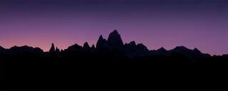 Jagged Patagonian mountains in silhouette beneath a star-speckled purple sky just before sunrise
