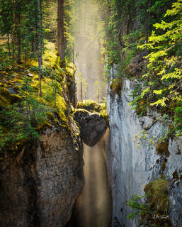 Heart-shaped rock held in place between two canyon walls with mist accentuating the light behind the rock.