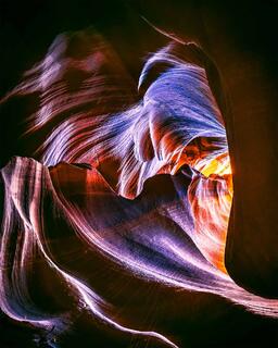 Light shines through a crevasse in the sandstone to outline the shape of a heart.