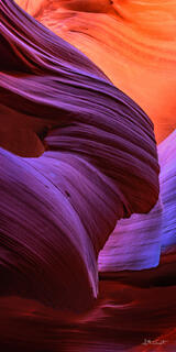 A mesmerizing display of sandstone layers in rich hues of crimson, purple, and orange, intricately sculpted by nature's forces over time.