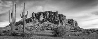 Black and white fine art landscape photograph of the Superstition Mountains rising from the Sonoran Desert floor with saguaro cactus in the foreground, AJ, AZ