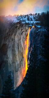 A golden glow transforms a cascading waterfall into a luminous spectacle, embodying nature's serene majesty at twilight.