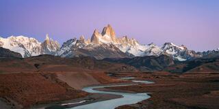 Monte Fitz Roy and Cerro Torre lit at sunrise above a braided river in the Patagonian steppe, Los Glaciares National Park, Argentina.