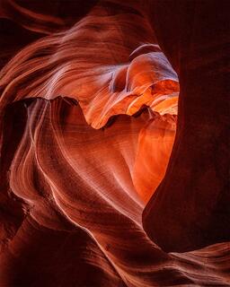 Light shines through a crevasse in the sandstone to outline the shape of a heart.