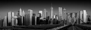 Empty boardwalk leading toward the Manhattan skyline, with a bridge framing the path and a calm, suspended city atmosphere.