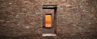 Ancient stone doorways aligned in a series of ruins in Arizona, with warm light illuminating the interior walls and passageways.