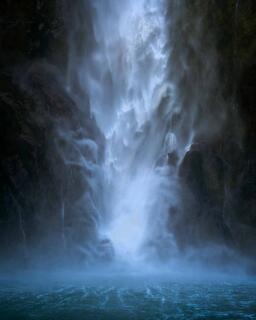The base of Stirling Falls in spray and mist where the cascade meets the fiord, long exposure, Milford Sound, New Zealand.