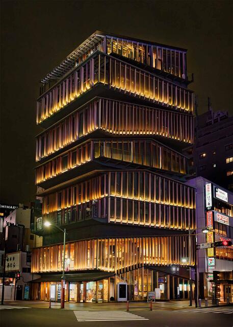 Illuminated modern building in Asakusa at night, layered architecture glowing softly, evoking calm, balance, and quiet presence