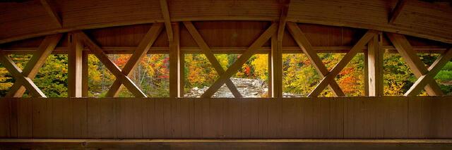 The interior Paddleford truss of the Albany Covered Bridge framing autumn foliage and the Swift River, White Mountains, New Hampshire.