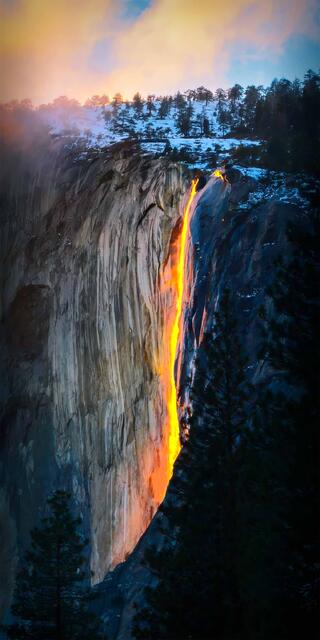 A golden glow transforms a cascading waterfall into a luminous spectacle, embodying nature's serene majesty at twilight.