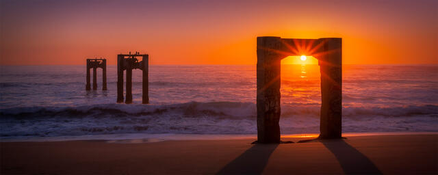 A sunset glimmering off the three free standing piers that extend out into the ocean