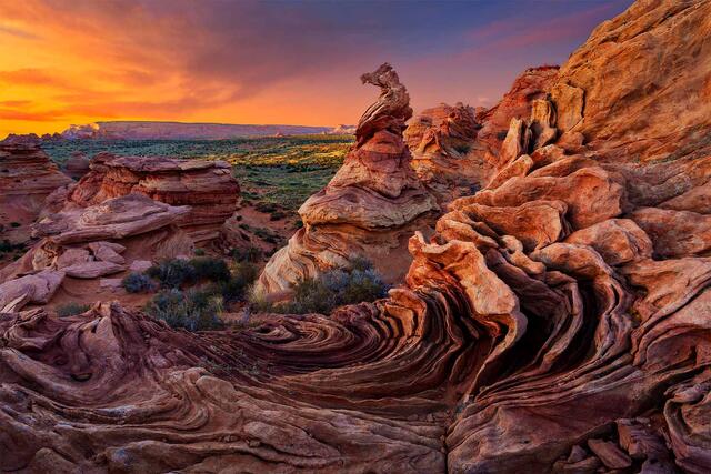 Swirling cross-bedded sandstone formations and a weathered hoodoo under an orange sunset sky, Coyote Buttes South, Vermilion Cliffs, Arizona