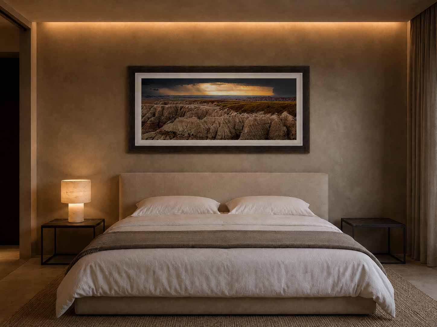 Badlands Burn shown as a framed print above an upholstered headboard in a lamplit bedroom, in an Elite Brown Gold Oxidized moulding with a white linen liner