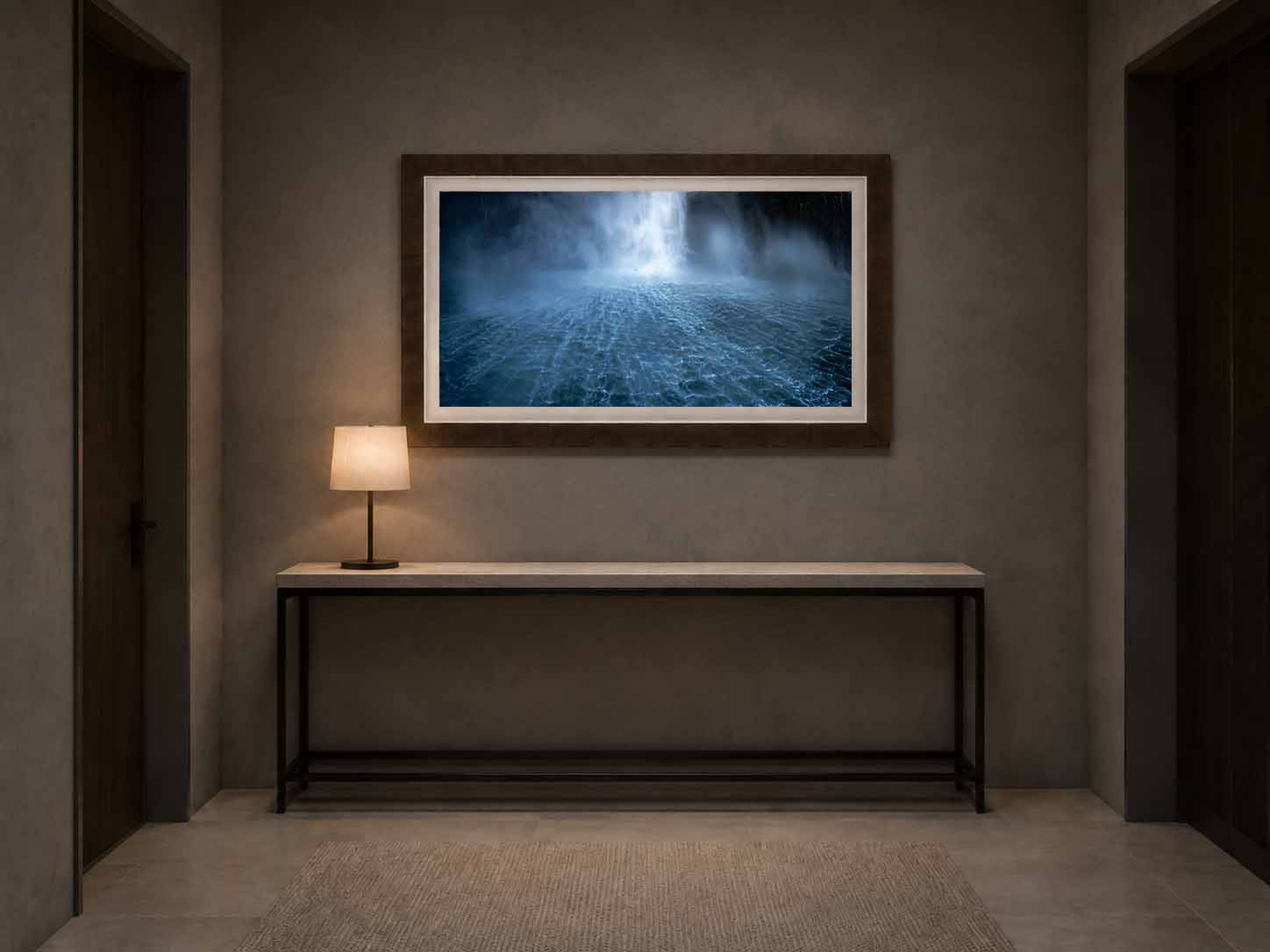 Beneath the Roar shown as a framed print above a steel and stone console in a dim plaster entry hall, in a Tabacchino Dark Ash moulding with a white linen liner