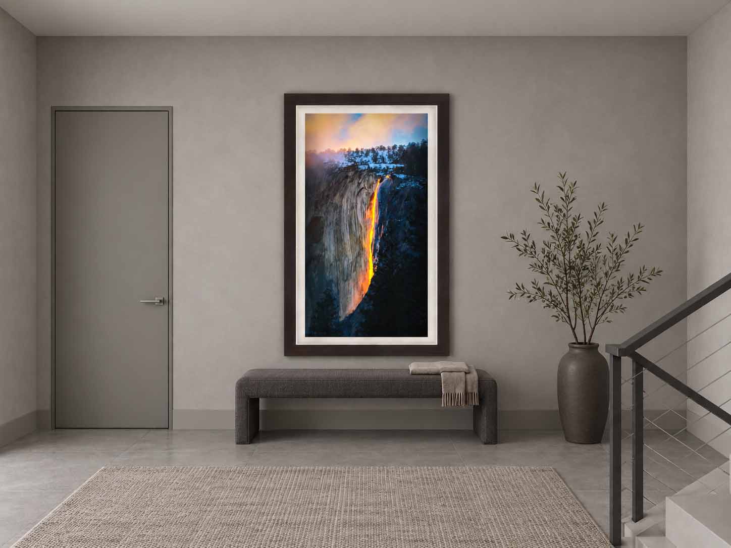 Horsetail Fall glowing at sunset on El Capitan in Yosemite, framed in dark wood with a white linen liner on a gray wall beside a stairway