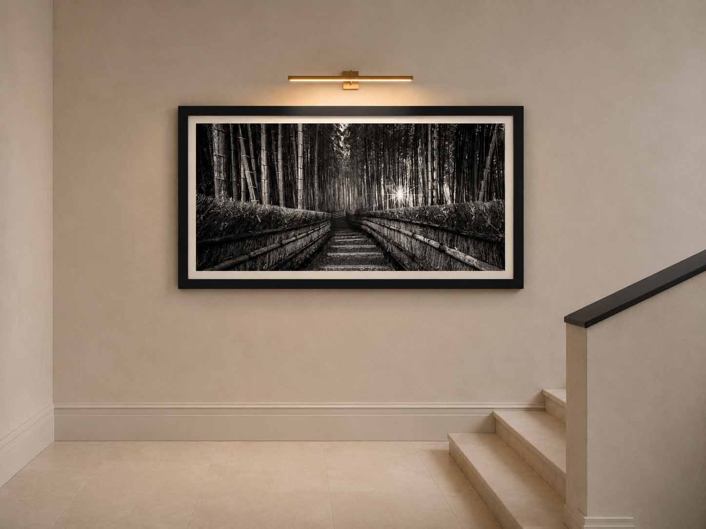 A black and white photograph of a bamboo forest stairway, framed in black with a white linen liner, lit by a picture light on a stair landing wall.