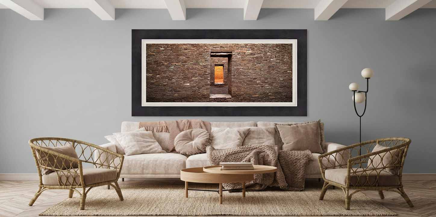 Aligned stone doorways at Pueblo Bonito in Chaco Canyon, framed in dark gray with a white linen liner above a stone desk in a quiet living room.