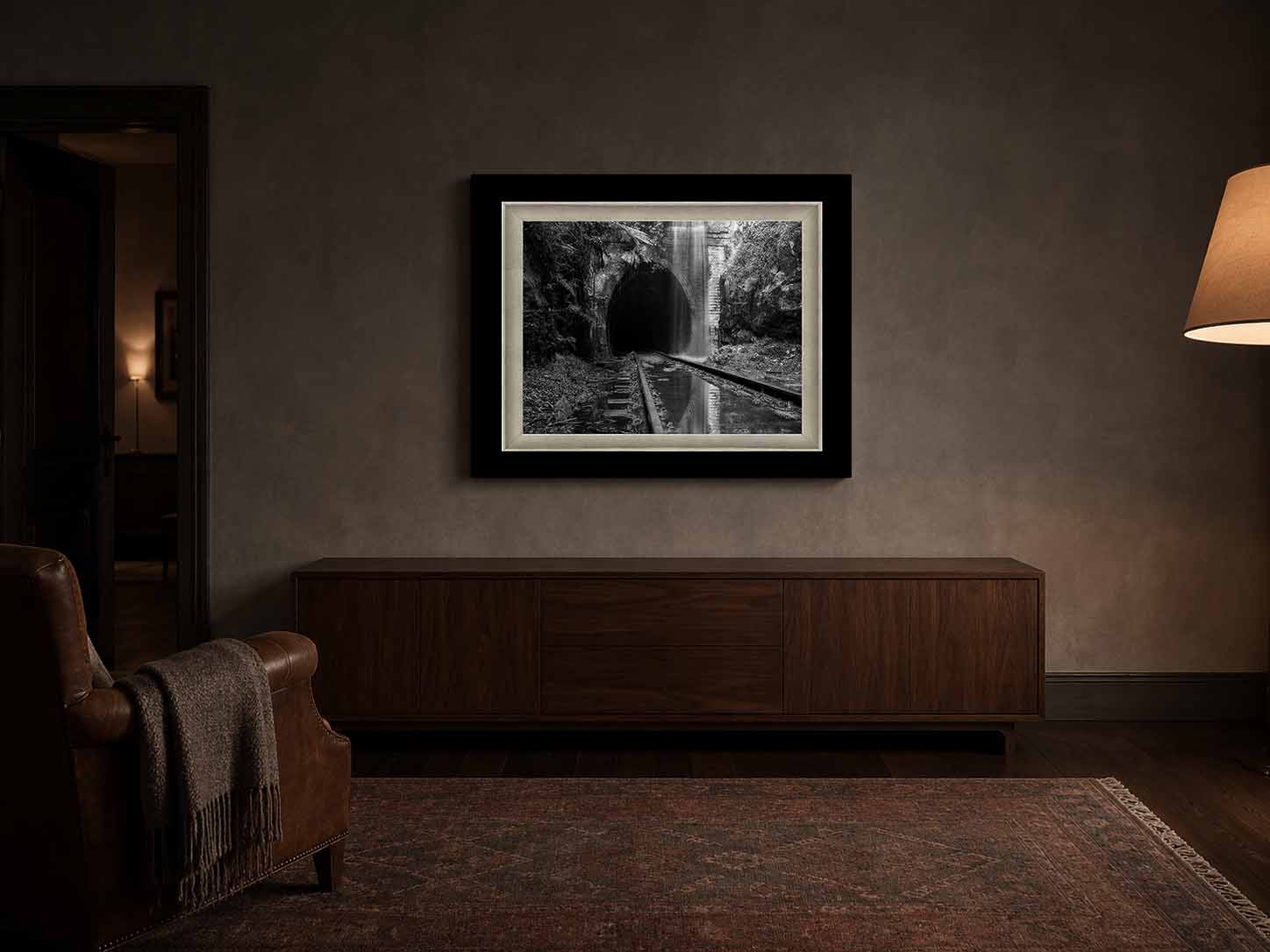 Reclaimed shown as a framed black and white print above a walnut cabinet in a lamplit study, in a Moda Satin Black moulding with a white linen liner