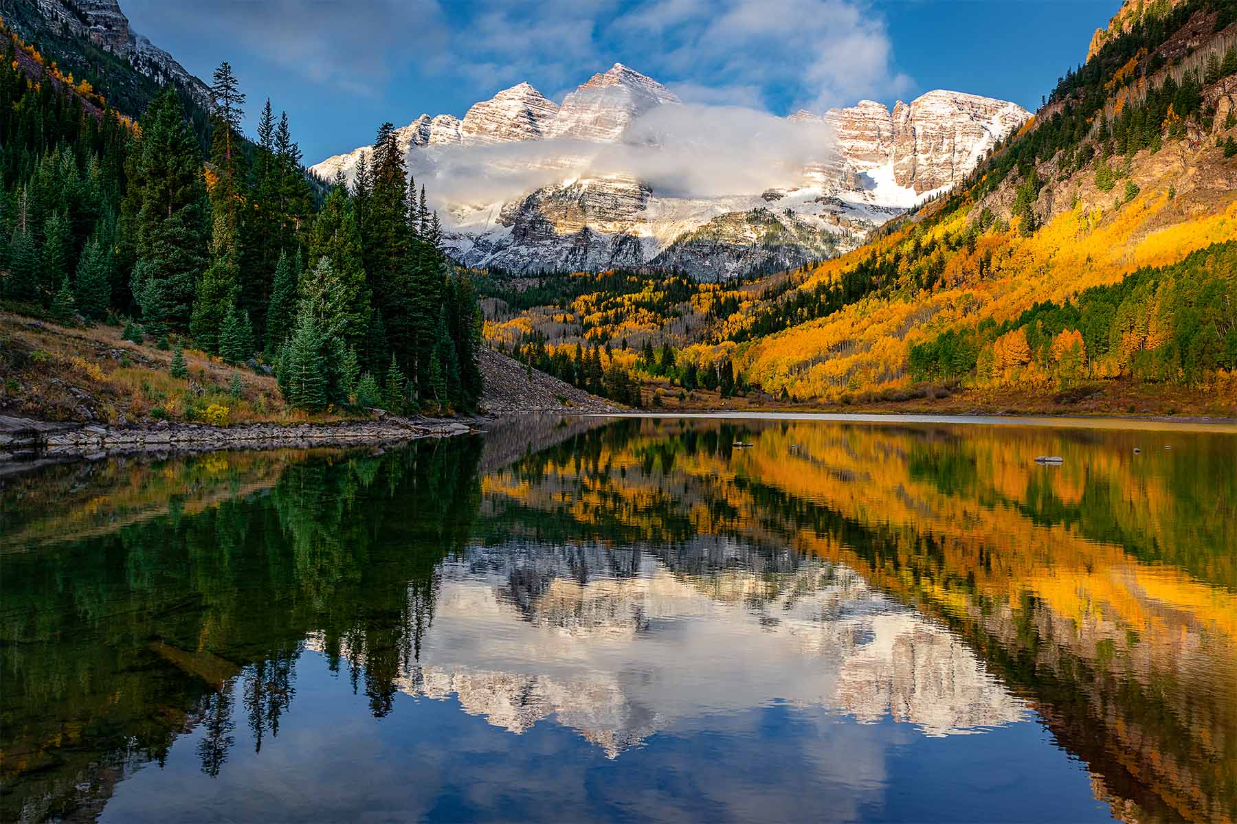 Resting in Reflection Snowcapped mountains and golden aspen trees reflected in a calm alpine lake during autumn in Colorado’s Maroon Bells Wilderness.