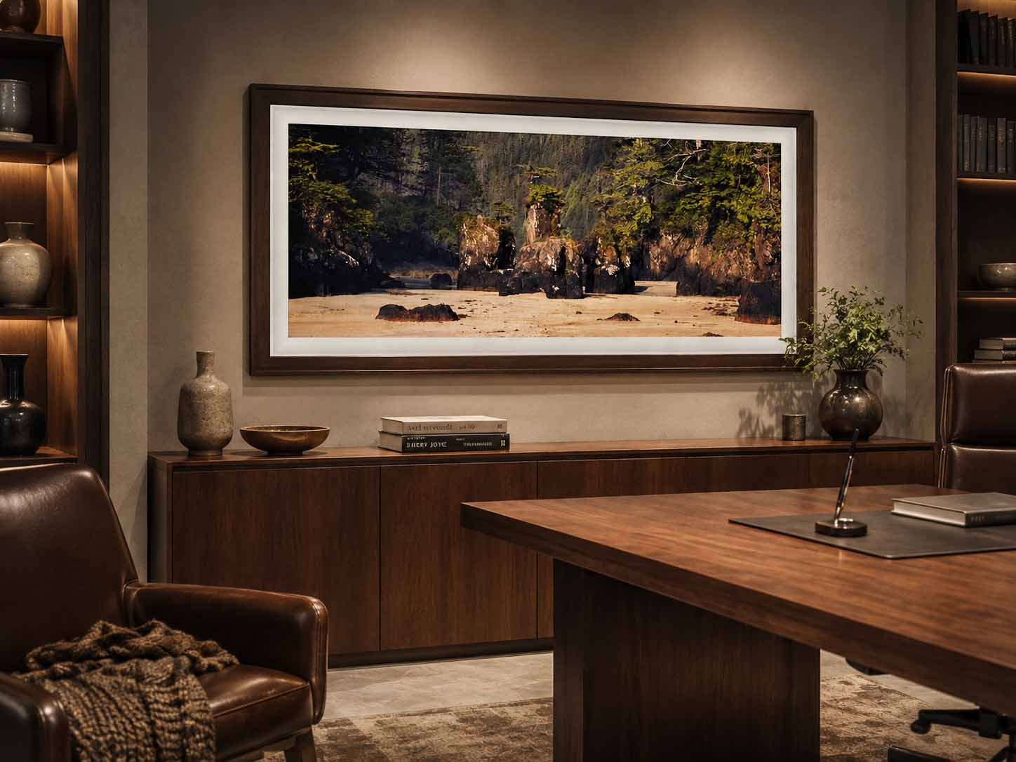 The Ancient Shore shown as a framed print above a walnut credenza in a warmly lit study, in a dark wood moulding with a white linen liner