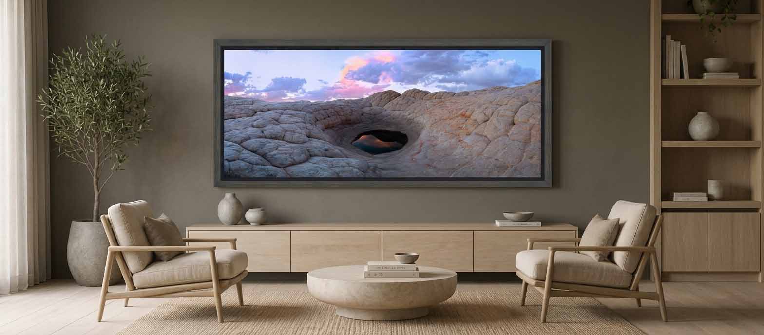 A still pool set in white sandstone at White Pocket, Arizona, framed in gray above a pale oak credenza in a warm living room with deep greige walls.